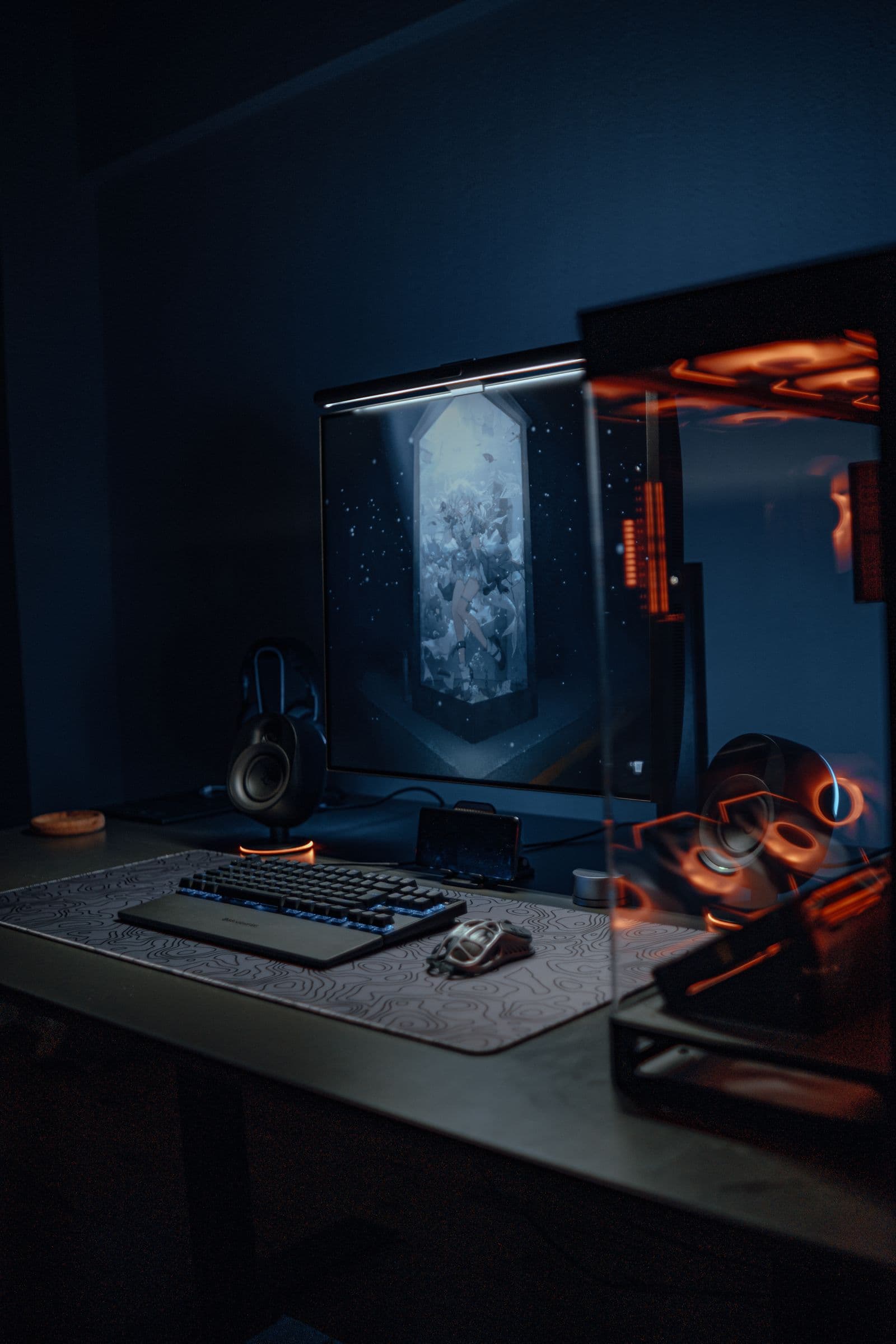 A moody RGB-lit gaming desk setup with mechanical keyboard and monitor